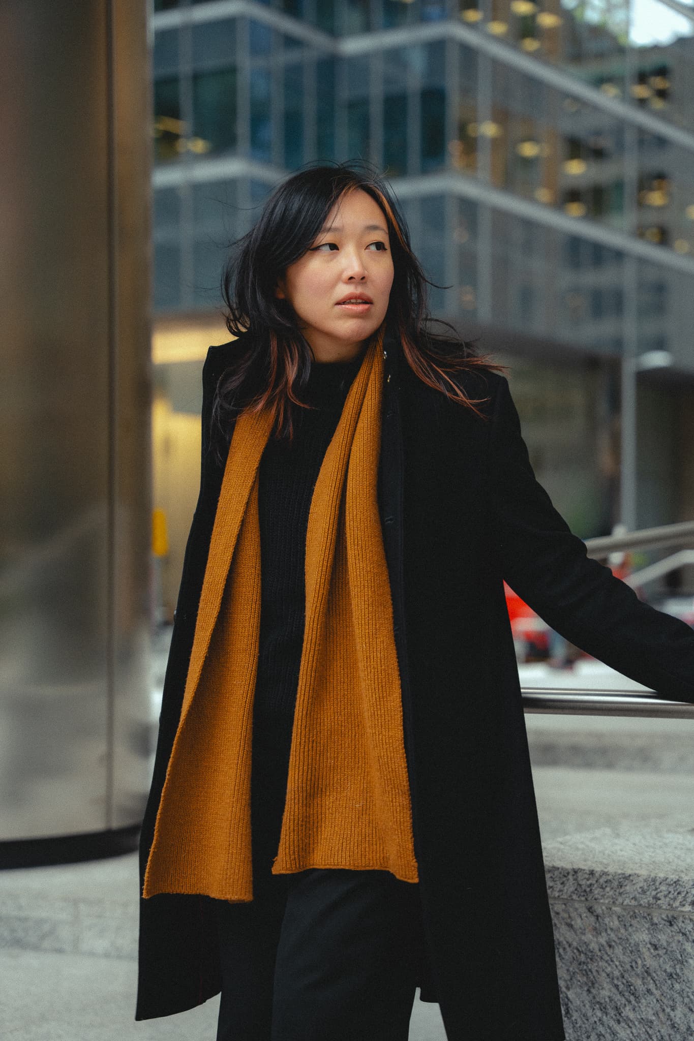 Woman with an ochre scarf near a modern glass building