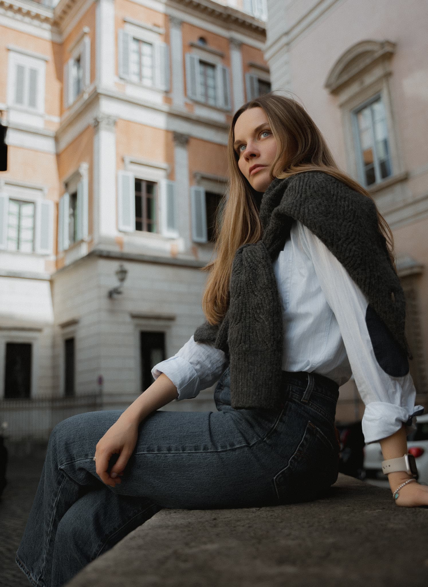 Woman seated on a railing in a European street scene